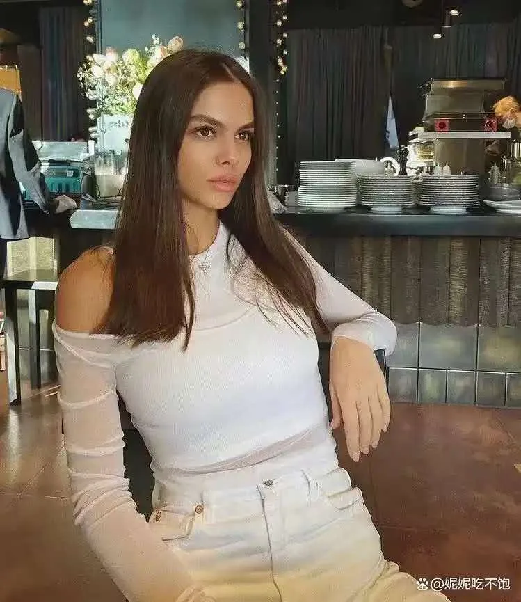 Adult woman in a white outfit seated indoors