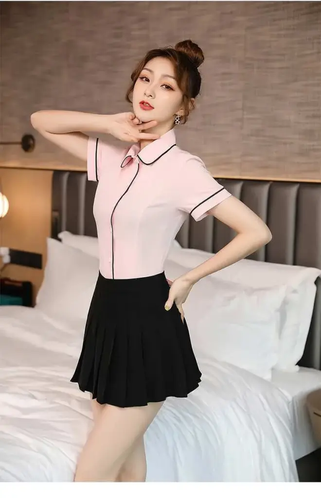 Adult woman in a pink collared outfit beside a bed